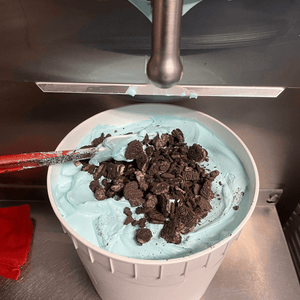 Homemade ice cream in a large white bucket with crushed Oreo's on top