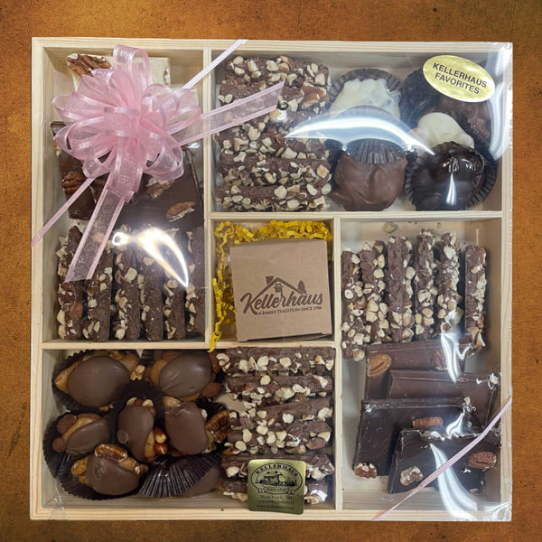 Wooden tray with 5 compartments containing butter crunch, bark, clusters, turtles, and a box with chocolate covered caramels.