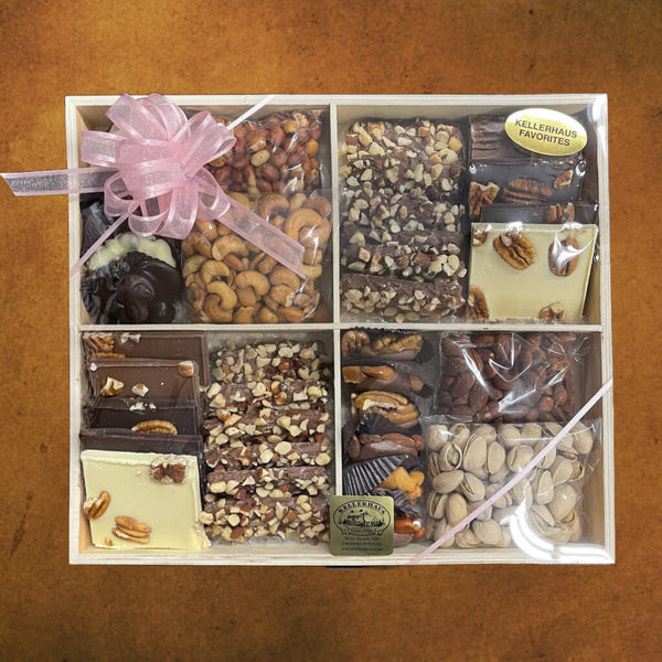 Wooden tray divided into 4 sections with 4 bags of different nuts, buttercrunch, chocolate pecan bark, chocolate caramel nut clusters, and chocolate nut clusters covered in plastic wrap and with a pink ribbon.