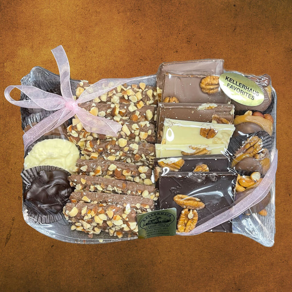 Large plastic tray with an assortment of buttercrunch, chocolate pecan bark, chocolate caramel nut clusters, and chocolate nut clusters wrapped in plastic and bow.