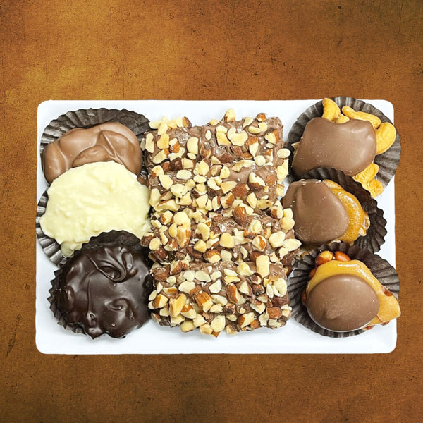 Small plastic tray with an assortment of buttercrunch, chocolate caramel nut clusters, and chocolate nut clusters.