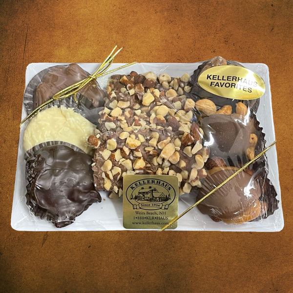 Small plastic tray with an assortment of buttercrunch, chocolate caramel nut clusters, and chocolate nut clusters wrapped in plastic and with a gold bow.