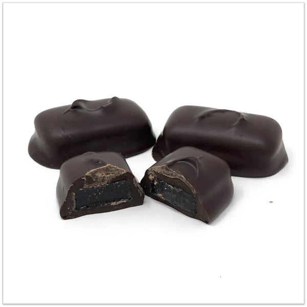 Dark chocolate cherry jelly cut in half in front of two other cherry jellies