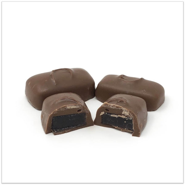 Milk chocolate cherry jelly cut in half in front of two other cherry jellies