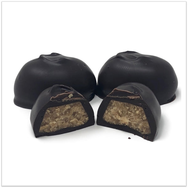 Dark Chocolate coffee cream cut in half in front of two other coffee creams