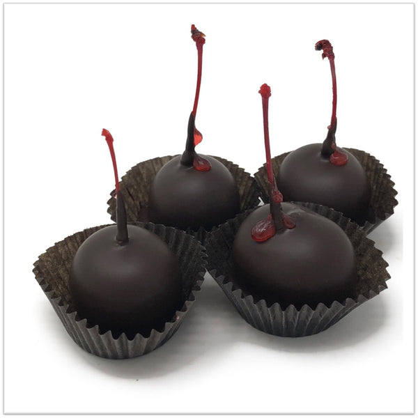 Four Chocolate covered cherries with juice running down the stem.
