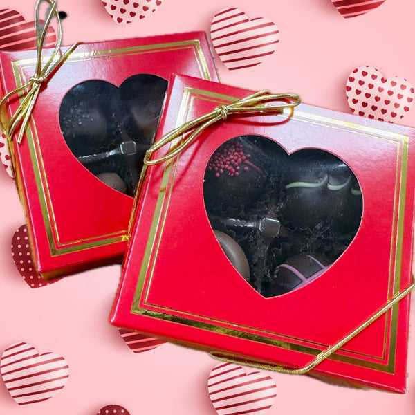 Two red boxes containing 4 pieces of assorted chocolates with gold bows and heart shaped windows to see chocolates inside.