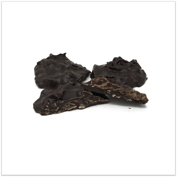 Dark chocolate coconut cluster cut in half in front of two other coconut clusters
