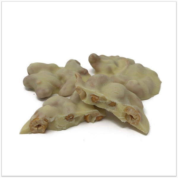 White chocolate cashew cluster cut in half in front of two other cashew clusters