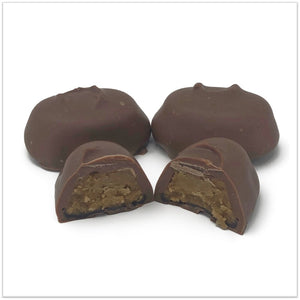 Milk Chocolate coffee cream cut in half in front of two other coffee creams
